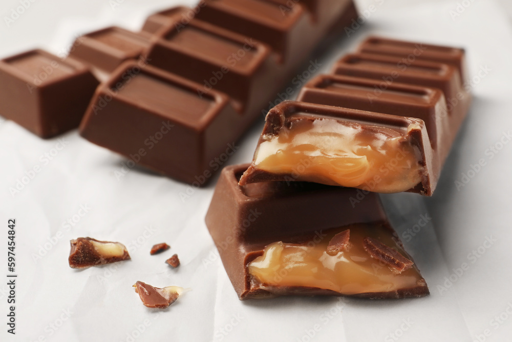 Tasty chocolate bars with caramel on paper, closeup view Tasty chocolate bars with caramel on paper, closeup view