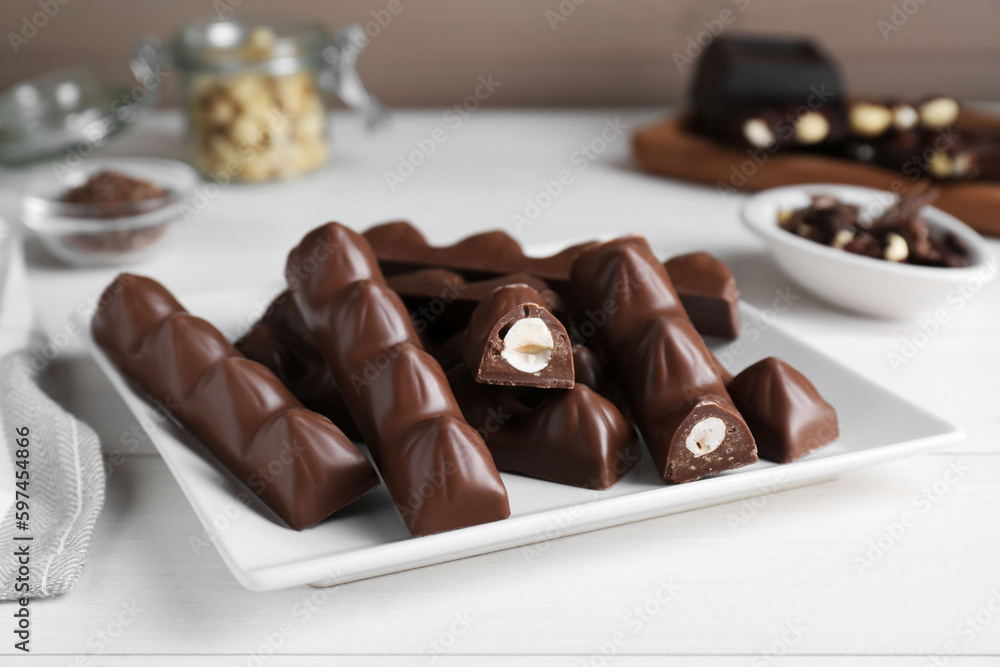 Tasty chocolate bars with nuts on white wooden table Tasty chocolate bars with nuts on white wooden table
