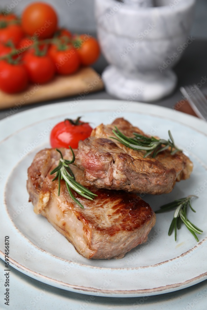 Delicious fried meat with rosemary and tomato on plate, closeup