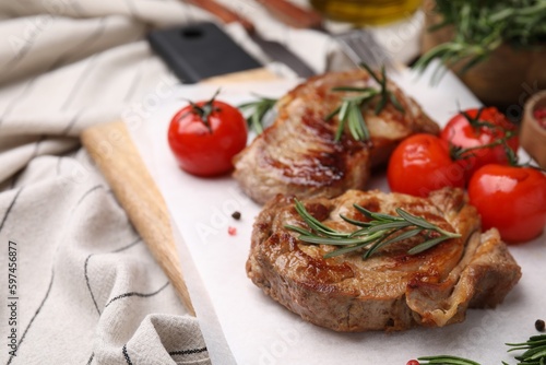 Delicious fried meat with rosemary and tomatoes on table, closeup. Space for text