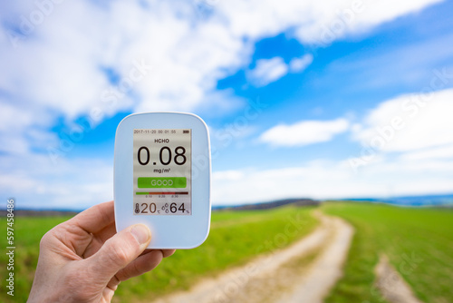 Foto air quality monitor in hand against the background of a summer green field shows