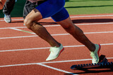 close-up legs male runner running in starting blocks sprint race, summer athletics championships