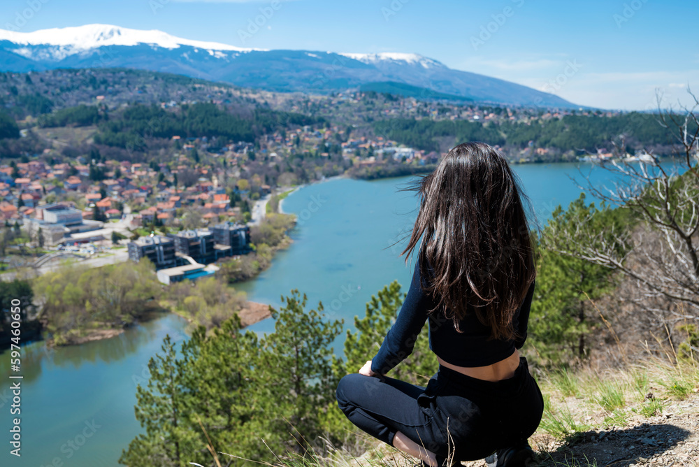 Woman standing  in the mountain high above a blue lake with stunning panoramic view .Traveling in the nature in Bulgaria 