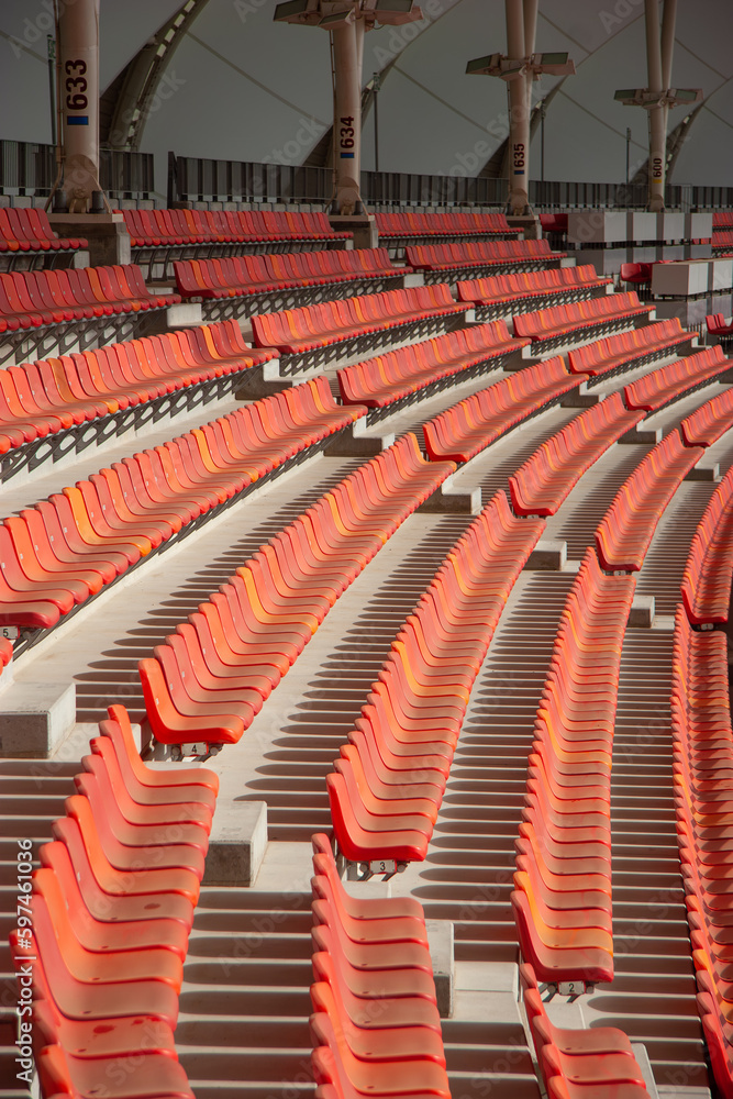 Naklejka premium Staggered sections of seating in stadium, red plastic box seats mounted to concrete