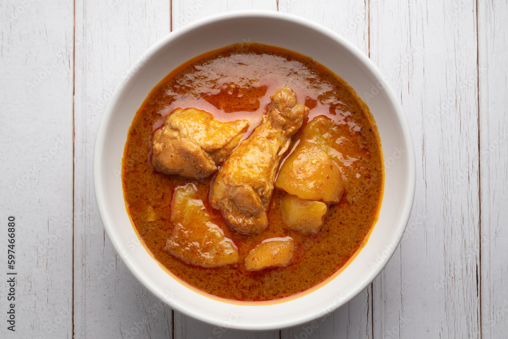 Chicken massaman with potato in white bowl on wooden table. Chicken massaman with potato in white bowl on wooden table.