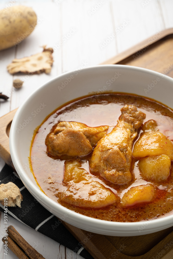 Chicken massaman with potato in white bowl on wooden table. Chicken massaman with potato in white bowl on wooden table.
