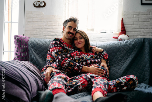 A couple looking at camera on the sofa at home during the Christmas holidays.
