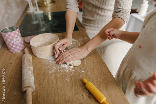 Mom rolling dough on kitchen table top at home. Mother and child knead dough, cook pizza, bake cookies, dumplings, croissants, pastries, pies. Family with kid having fun. Food preparation on weekend