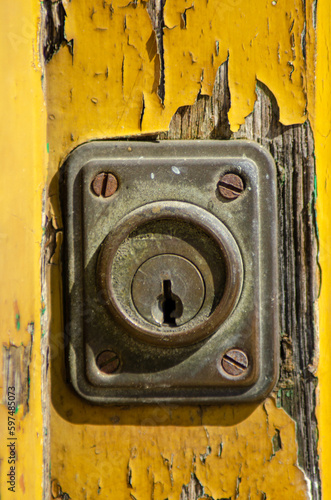 Detail of the lock of an old wooden door painted yellow.
