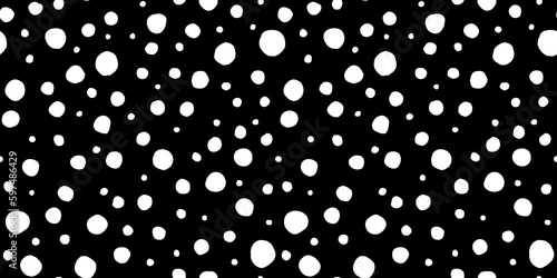 Seamless polkadot pattern made of playful hand drawn white paint polka dot circles or snow spots on black background. Simple abstract blender motif texture in a trendy bold whimsical doodle art style.