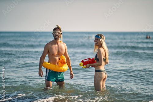 Crazy  man with rubby duck and smiling woman with water gun at beach.fun at the beach in summer holiday. photo