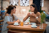 Young hipster women having coffee together, in cafe, talking.