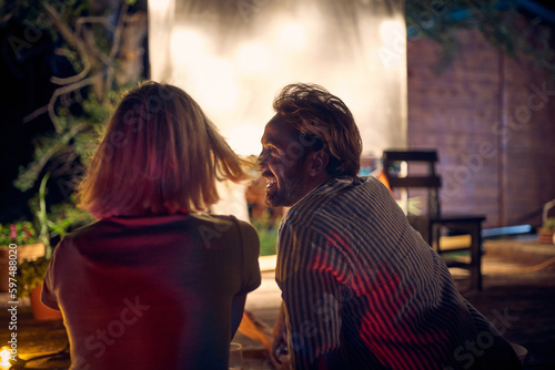 A young couple enjoying a night cinema in the bar at the river bank. Night, summer, bar, river