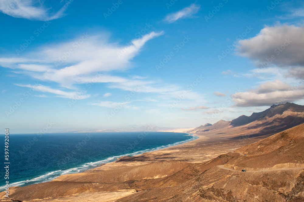View Cofete beach on Jandia Peninsula in Fuerteventura, Canary Islands. Cofete beach is approximately 14 kilometers long with crystal clear turquoise waters, located in the Jandia Natural Park.