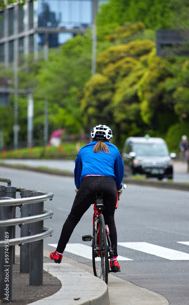 Naklejka premium 東京の街の道路で自転車を乗って運動している女性の姿