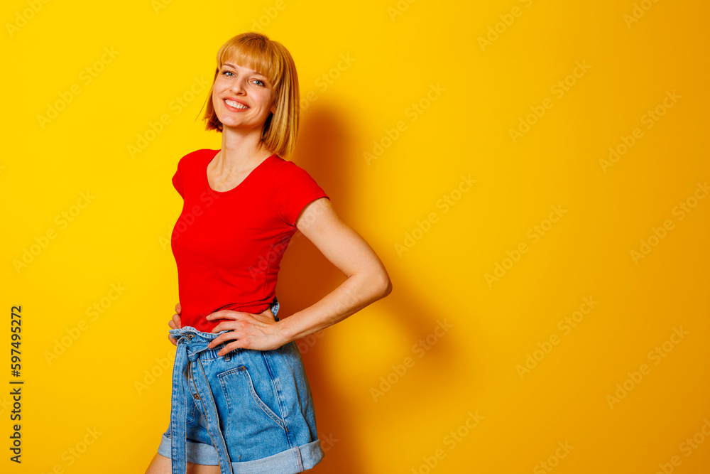 Woman holding hands on hips on yellow background Woman holding hands on hips on yellow background