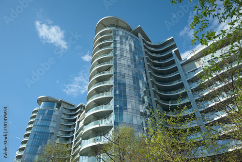 Glass facade. Low-angle view of modern high rise residential building in Kyiv. Blue sky with white clouds in the background. Modern architecture from glass and steel. Concept of real estate in Kyiv