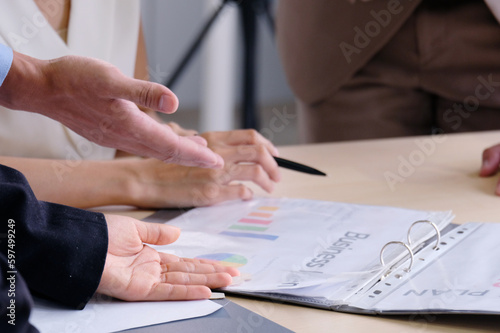 Businessman hand pointing and holding documents at meeting.