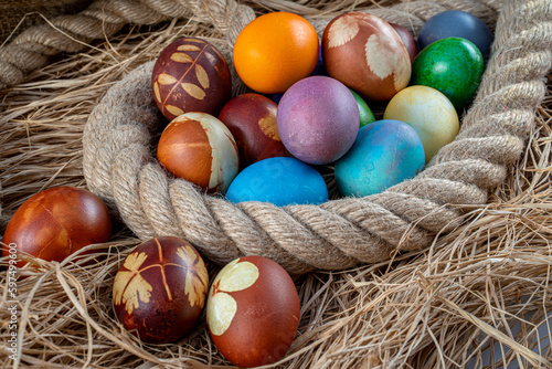 Multicolored Easter eggs in straw and rope. Pastel colored Easter eggs.