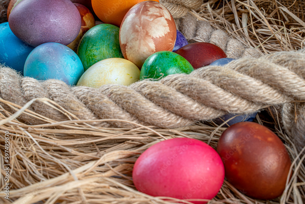 Multicolored Easter eggs in straw and rope. Pastel colored Easter eggs. Multicolored Easter eggs in straw and rope. Pastel colored Easter eggs.