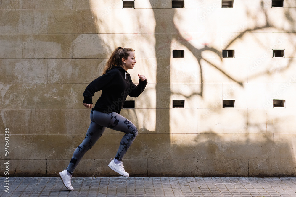 Active sportswoman running on sidewalk in city Active sportswoman running on sidewalk in city