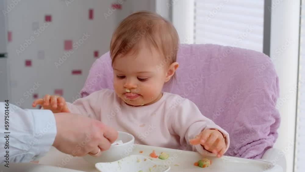 Toddler eat with a spoon, new skill in learning how to eat by himself. Funny baby girl on stage to weaning Toddler eat with a spoon, new skill in learning how to eat by himself. Funny baby girl on stage to weaning