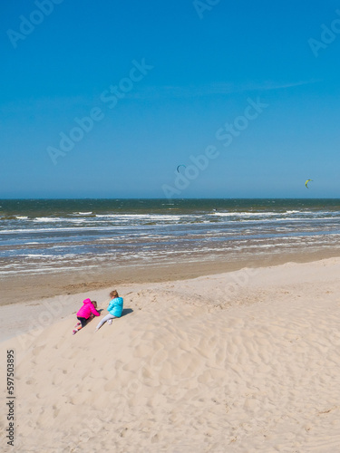 Enfant jouant sur le sable et regardant les kitesurfs