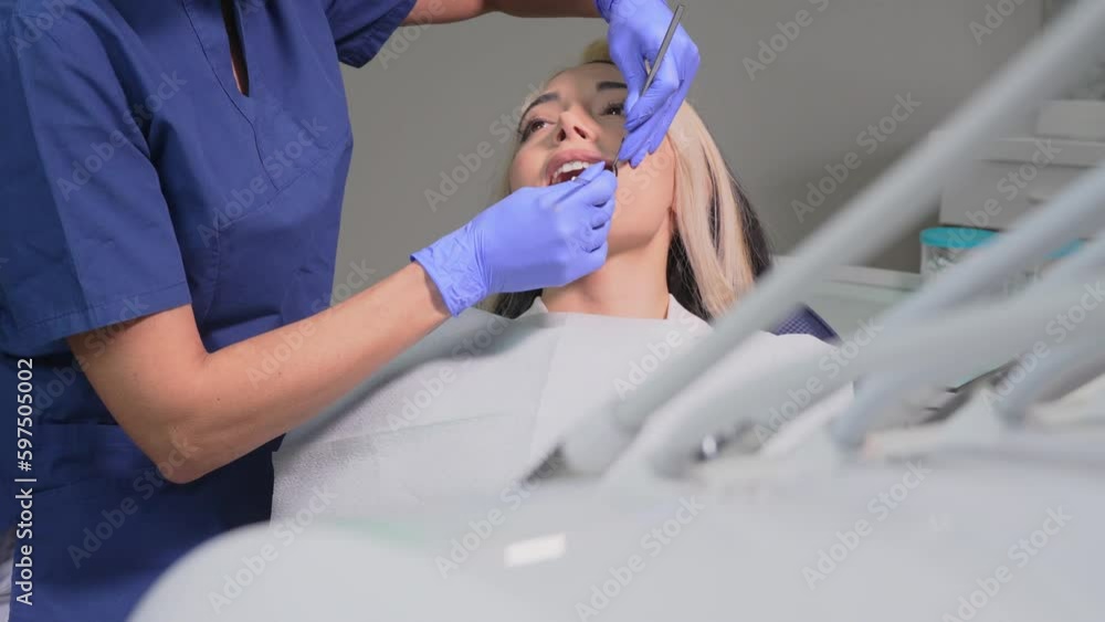 Beautiful young woman doing tooth examination in dental office. dentist examined tooth of young girl in dental clinic. Attractive female patient lying on dental chair receives dental treatment Beautiful young woman doing tooth examination in dental office. dentist examined tooth of young girl in dental clinic. Attractive female patient lying on dental chair receives dental treatment