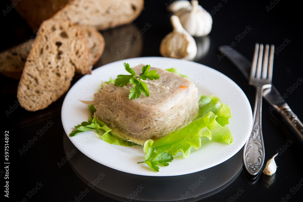 Boiled chicken meat aspic in meat gelatin broth in a plate Boiled chicken meat aspic in meat gelatin broth in a plate