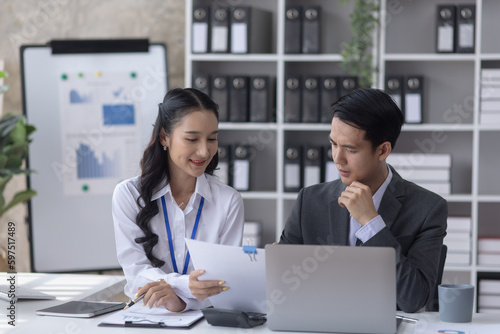 Two employees working at table in a modern office, Asian man and a woman work at office desk, Business campaign result and project planning concept, financial planning, 