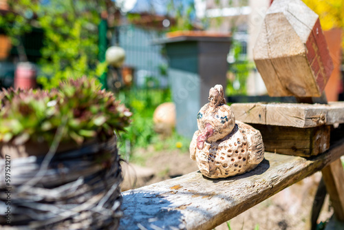 Handmade, abstract bird figure stands on a wooden bench in the garden

