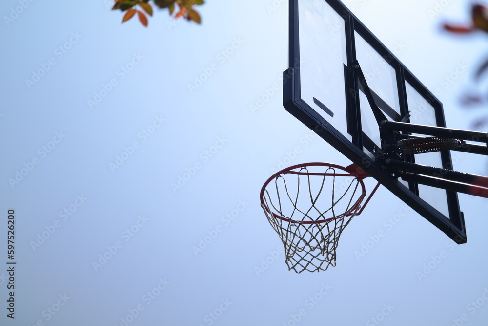 Silhouette of a basketball hoop against a blue sky