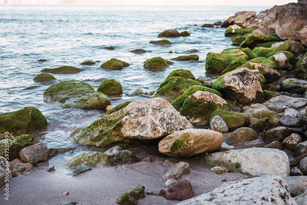 Rocks on the seashore some covered with green moss Rocks on the seashore some covered with green moss
