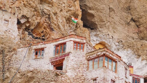 Indian flag waving above the old Phugtal monastery in Zanskar, Ladakh, India. Indian tricolored flag on a remote monastery in the Ladakh region. Indian flag on the old monastery built in cave.