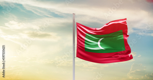Maldives national flag waving in beautiful sky. The symbol of the state on wavy silk fabric.