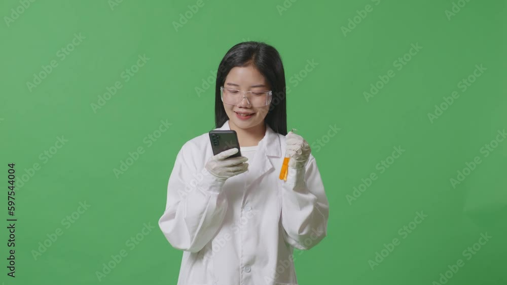 Asian Woman Scientist Holding A Test Tube Of Orange Liquid And Using Smartphone While Standing On The Green Screen Background In The Laboratory
Asian Woman Scientist Holding A Test Tube Of Orange Liquid And Using Smartphone While Standing On The Green Screen Background In The Laboratory