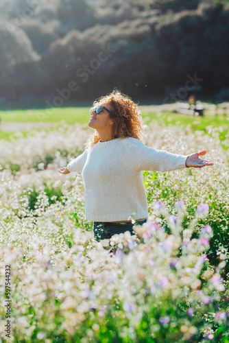 Freedom and happiness enjoying the nature. One woman happy in the middle of a white blossom flowers field opening arms and smiling up. Summer travel holiday vacation people lifestyle. Leisure activity photo