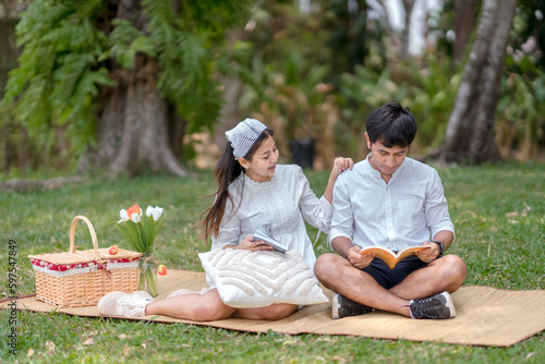 Man and woman sitting in the park reading a book on weekends
