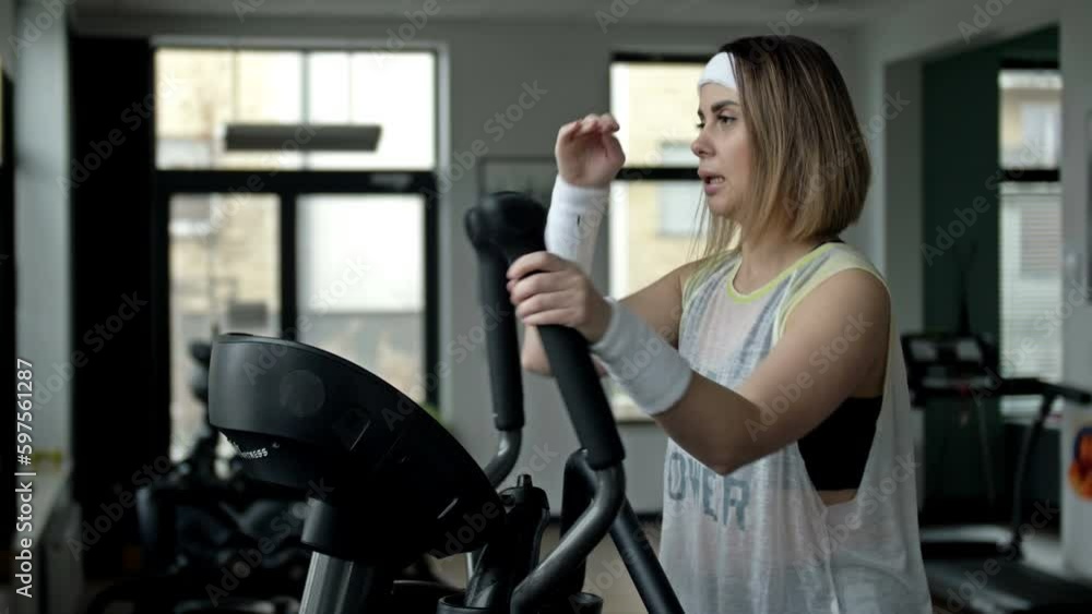 Strong young beautiful woman is engaged in a gym on an ellipsoid. Concept of sport and healthy lifestyle. Strong young beautiful woman is engaged in a gym on an ellipsoid. Concept of sport and healthy lifestyle.