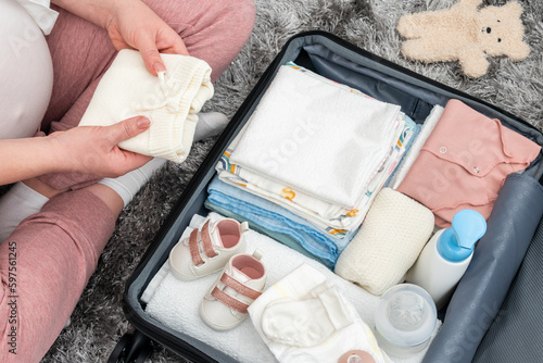 Pregnant woman packing suitcase for maternity hospital at home