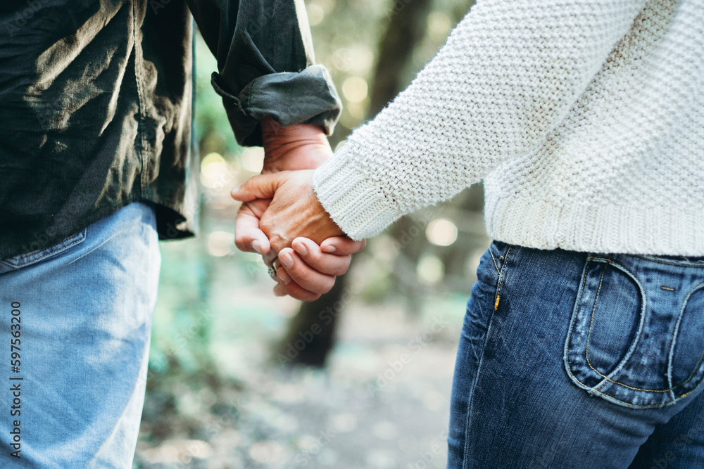 Close up back view of man and woman holding hands with love and relationship. Concept of togetherness. Couple in love enjoying outdoors together. Healthy positive relationship. Casual clothes people