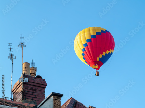 Hot air balloon rising above house roof tops clear sky