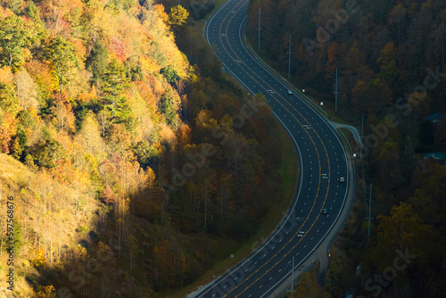 Aerial view of highway road in North Carolina through Appalachian mountains in golden fall season with fast moving trucks and cars. Interstate transportation concept