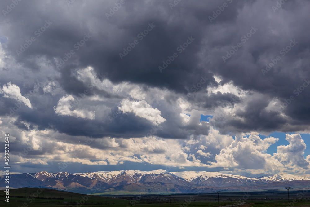 Panoramic landscape with snowy mountains and dramatic clouds