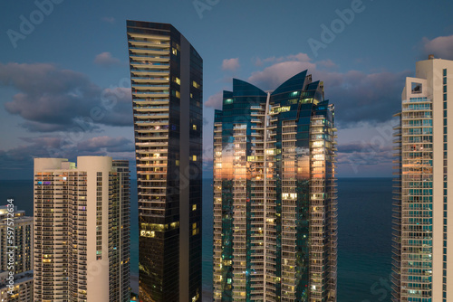 Night urban landscape of downtown district in Sunny Isles Beach city in Florida, USA. Skyline with brightly illuminated high skyscraper buildings in modern american megapolis