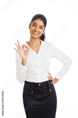 Cheerful young business woman showing ok hand sign isolated on white.