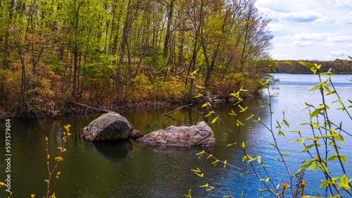 Fototapeta Naklejka Na Ścianę i Meble -  Lincoln Woods State Park and Olney Pond spring landscape with glacial rocks in the water and new sprouts on the trees near Providence, Rhodes Island, USA