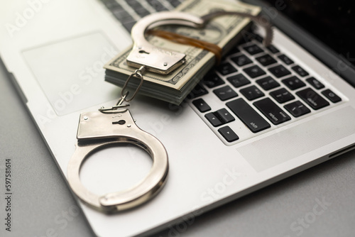 Handcuffs keyboard and dollars above photo
