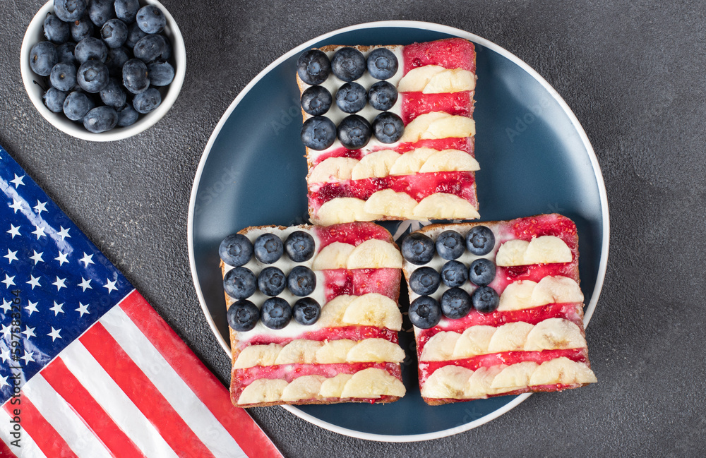 Obraz premium American flag sandwiches with blueberry, banana and berry jam on toast bread on blue plate, View from above