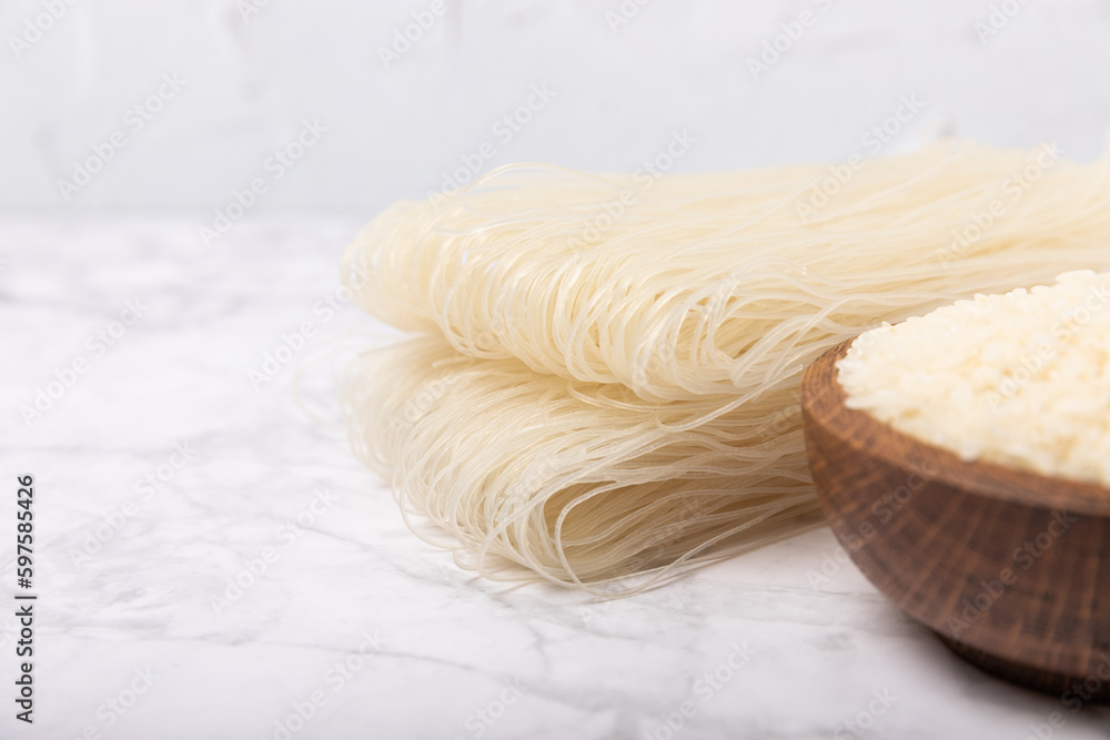 rice noodles. Noodles with rice flour on a white marble background. Funchoza. Dry rice noodles.Close-up.Copy space. Place for text. rice noodles. Noodles with rice flour on a white marble background. Funchoza. Dry rice noodles.Close-up.Copy space. Place for text.
